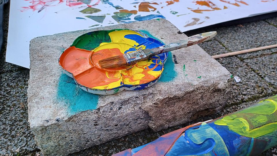 Malpalette mit Farben und Pinsel auf einem Stein