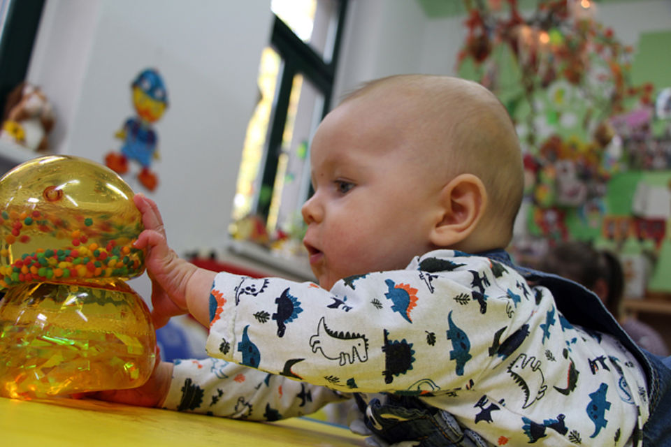 Baby liegt auf dem Bauch und spielt mit bunten Bällen